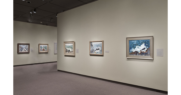 Cream-colored gallery walls with framed paintings hanging on the two visible walls.