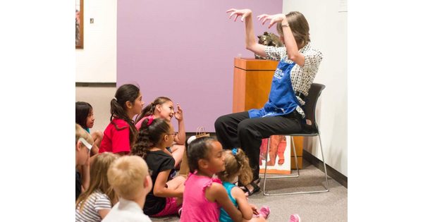 A Carter staff member sits in a chair in front  of group of children seated on the floor.