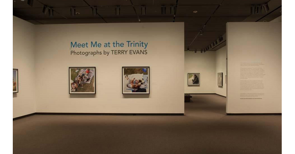 View of gallery featuring exhibition title wall and two framed photographs hanging on cream-colored walls.