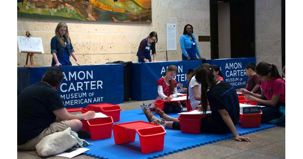 Families sit on the floor of the Museum&#039;s Atrium working on art projects.