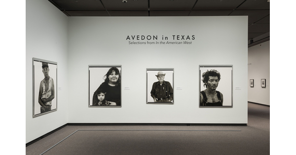 View of exhibition title wall showing three framed black-and-white portraits hanging on a white wall.