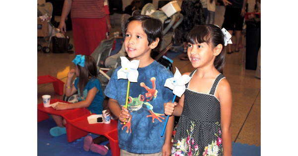 Two children hold paper pinwheels.