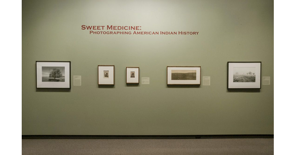 Light green title wall with five framed photographs hanging under the exhibition title.