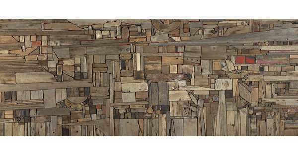 A detail of a flat abstract assemblage of wood pieces in various shapes, sizes, and colors fitted together perfectly like puzzle pieces.