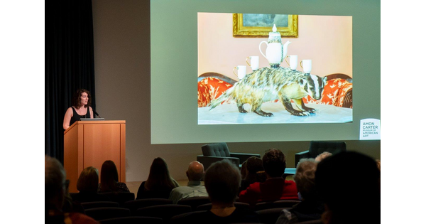 In the Carter&#039;s auditorium, a woman stands at a podium next to a screen showing artwork.