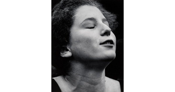 Black and white photo of a pre-teen holding her head to the sky; her eyes are closed