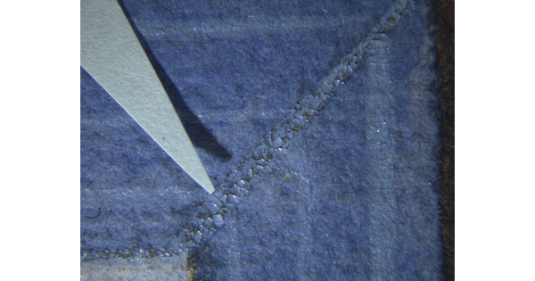 A close-up detail of flaking paint on an artwork.
