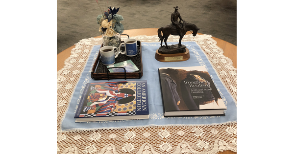 A table with two Museum catalogues, a sculpture, and a tray with tea cups.