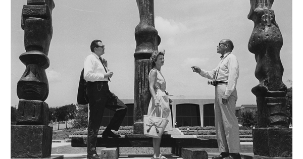 Black and white photo of three people standing on the Carter&#039;s plaza in front of three sculptures.