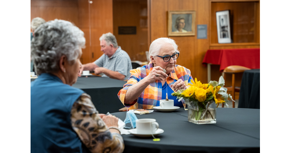 Adults sit at tables in the Carter&#039;s Lounge sipping tea.