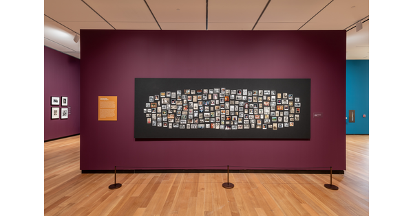 Photographs of various sizes and formats mounted on a black background and hung on a wall in &quot;Black Every Day.&quot;