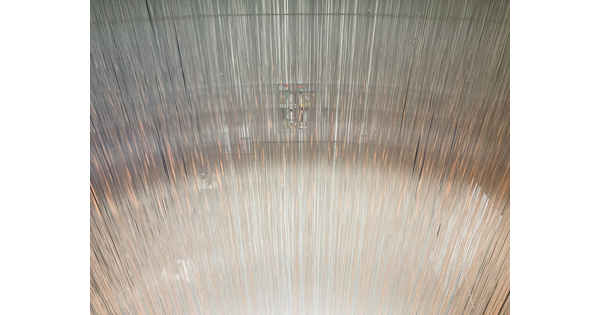 A detail of a sculpture that is made up of thousands of clear, glass threads.