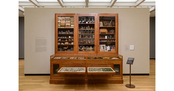 A wood cabinet with shelves behind glass doors and several drawers, two of which are pulled open.