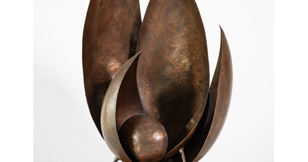 A bronze sculpture with leaf-like shapes reaching upward and a sphere cradled at the bottom of the flat, broad leaves.