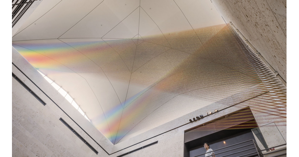 A large installation of multicolored sewing thread that stretches from one wall to the ceiling in the Carter&#039;s Atrium and looks like a rainbow.