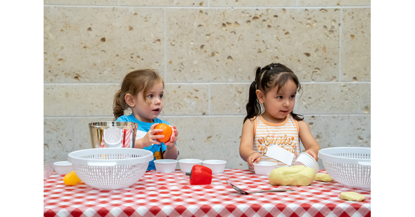 Two small children play with toy fruits and vegetables at a table in the Carter&#039;s Atrium.