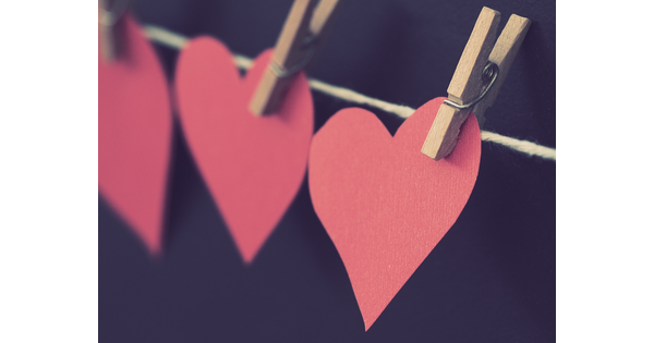 A photo of construction paper hearts attached to a string with wood clothespins.