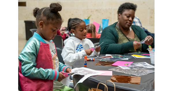 An adult and two children make art at a table in the Carter&#039;s Atrium.