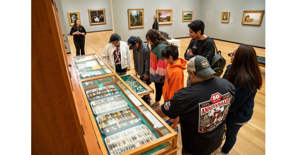 A group of people of a variety of ages stand in a Carter gallery looking at interactive artwork.