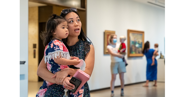 A woman and a young child she is holding on her hip look at art in a Carter gallery.