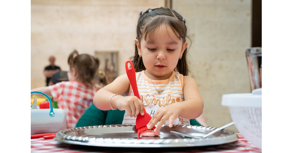 A child paints an object on a table in the Carter&#039;s Atrium.