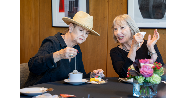Two White women at a table in the Carter's Lounge enjoying tea and cakes.