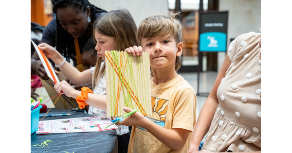Children in a Carter galley make artwork at a table; one of them hold up his work to show.