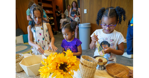 Three young children stand at a table making artwork in the Carter&#039;s Family Pop-up space.