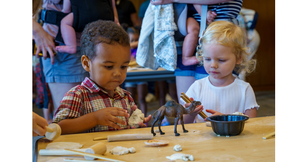 Two small children at a table making artwork from clay.
