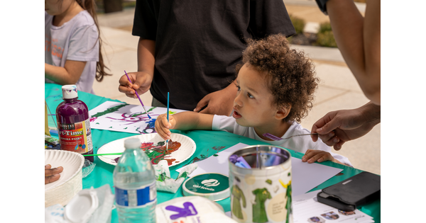 A child uses paints to make an artwork at a table in the Carter&#039;s Atrium.