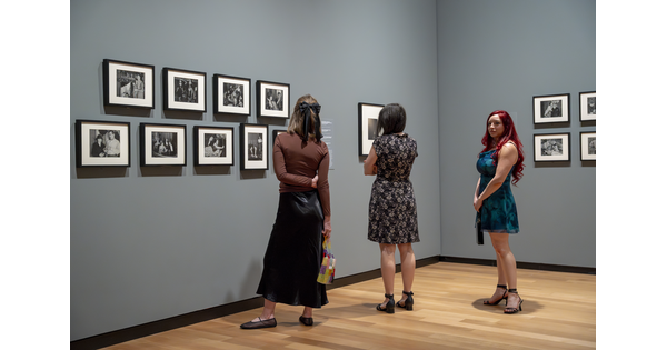Three people look at framed photographs on a gallery wall at the Carter.