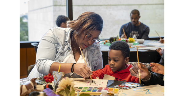 An adult and a child paint with watercolors at a table in the Carter&#039;s Family Pop-Up space.