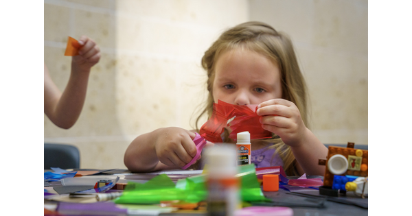A child cuts and glues colorful paper to make artwork in the Carter Atrium.