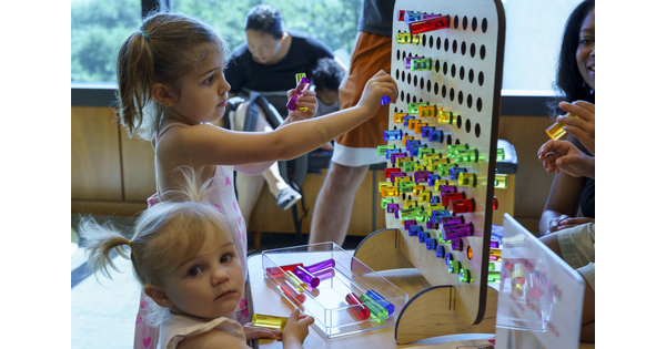 Two small children play with a colorful pegboard in the Carter&#039;s Family Pop-Up space.