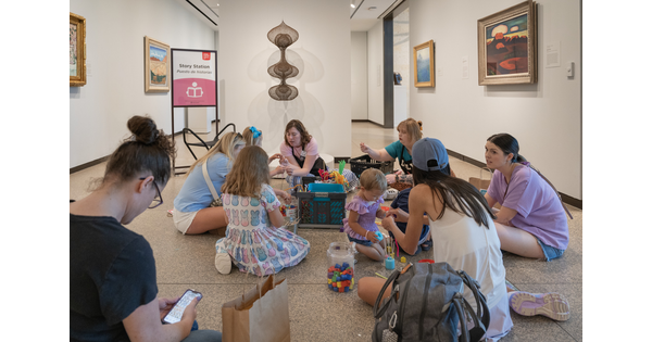 A group of adults and children sit on the floor of a Carter gallery looking at artwork.