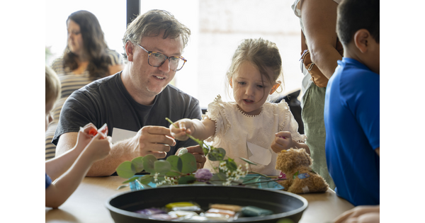 An adult and child make art together at a table in the Carter&#039;s Family Pop-Up space.