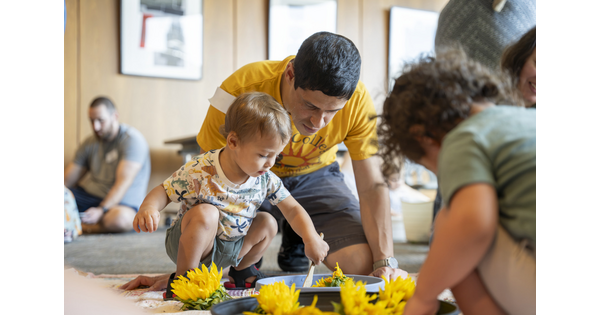 An adult and child on the floor of the Carter&#039;s Family Pop-Up space making art together.