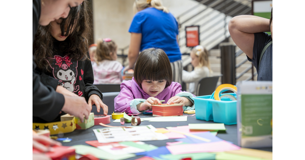 A child and several adults make art at a table in the Carter&#039;s Atrium.