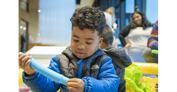 A dark-skinned child plays with a colorful toy on the floor of a Carter gallery.