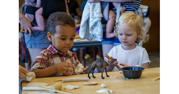 Two very young children make artwork with clay at a table in the Carter&#039;s Pop-up Lounge.