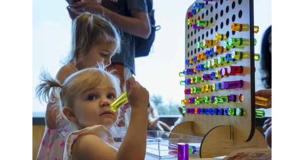 A young White child places colored pegs into a pegboard in a Carter gallery.
