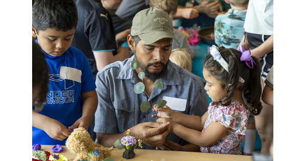 Two brown-skinned children and an adult make sculpture at table in the Carter&#039;s Pop-up Lounge.