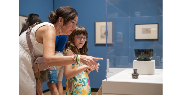 An adult and a child look at artwork in a display case in a Carter gallery.