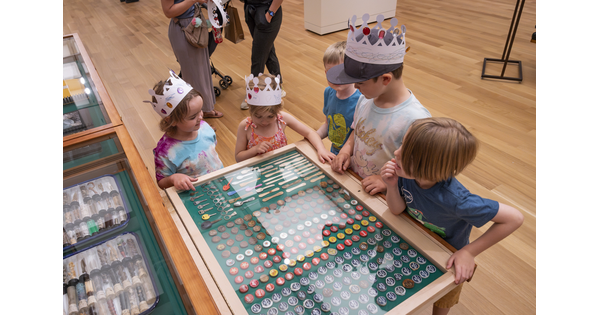 Five children stand around an open drawer in "The Texas Cabinet" looking at its contents.