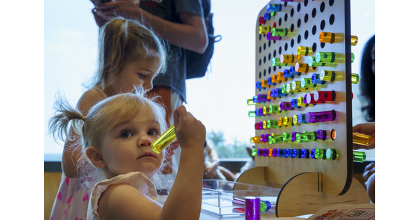 Two children play with large colored pegs and a pegboard in the Carter's Pop-Up Space.