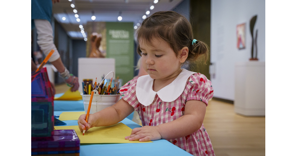 A White child draws at a table in a Carter gallery.