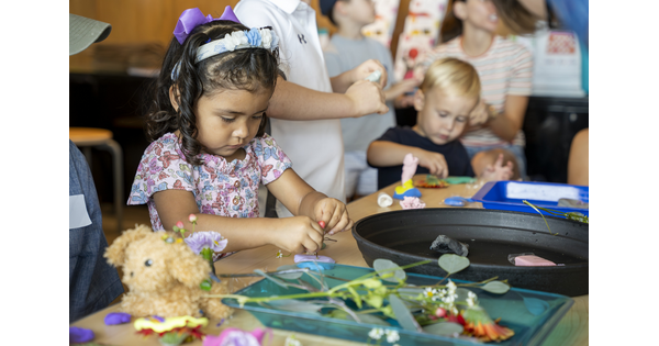 Two toddler-age children make art next to each other at a table in the Carter's Family Pop-Up Space.