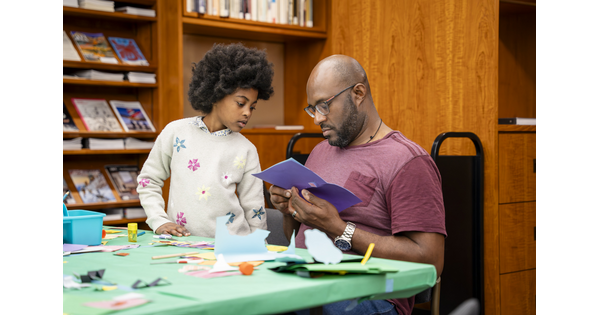 A Black man and pre-teen make art together at a table in the Carter Library.