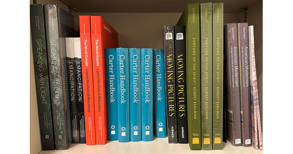 A bookshelf of coffee-table books about American art.