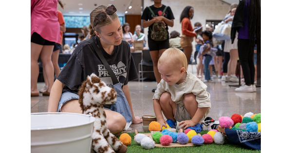 A small child plays with colorful pom-poms in the Carter's Atrium.